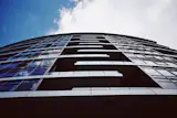 Looking up at balconies and windows in a newer rise near The Fields park.