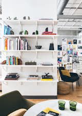 Open shelving and books with a sea of posters in the rear brings color and life to the sea of whites, grays, and light wood flooring.