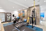 Fully equipped gym with contrasting concrete walls elevate the homes amenities.