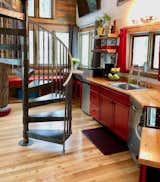 Kitchen, Refrigerator, Dishwasher, Range, Wood Counter, Colorful Cabinet, Wood Cabinet, Open Cabinet, Light Hardwood Floor, Ceiling Lighting, and Drop In Sink Montana Treehouse Retreat Kitchen with Iron Spiral Staircase and Open Shelves  Photo 2 of 7 in The Montana Treehouse Retreat