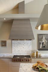 Stove hood is an iconic shape, done in horizontal grain oak stained dark.  Marble mosaic tile over a Wolf range top.  Photo 10 of 12 in A New Beginning by Nancy Van Natta Associates