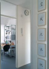 The entrance hallway. To the right the Japanese symbols for the five elements: void, wind, fire, water and earth. To the left the entrance to the kitchen. Wall clock by Mondaine.