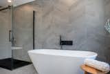 Chevron slate tiles by ITAL NORD CERAMICS cover the entire walls of both the bath area and shower space.