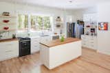 The all-white kitchen has an Aga stove, work island, floating shelves, and a coffee station.  Photo 4 of 11 in The Privacy House by Arielle Condoret Schechter, AIA: Simple, Modern, Net Zero by Kim Weiss