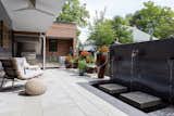 The patio includes an outdoor kitchen (background) and a custom-fabricated steel water fountain.