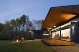 The roof's deep overhang provides covering for the deck and exposes the rich cypress wood overhead. The dark siding is Nichiha fiber cement.