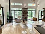 Living Room, Wood Burning Fireplace, Coffee Tables, Sofa, Pendant Lighting, Chair, Bookcase, Light Hardwood Floor, and Wall Lighting View from the kitchen through the dining and living spaces to the forest beyond the house.   Photo 8 of 16 in A Jewel Box for a Special Ops Soldier by Kim Weiss