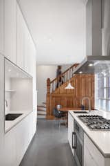 The kitchen in the Winchester Residence features plywood cabinets with white Fenix cladding.  RobitailleCurtis moved the rear service stair forward into the kitchen to allow a new stair to the basement to be concealed beneath it.