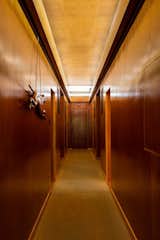 A long clerestory illuminates the hallway dividing the bedroomwing of the house. The door at the end originally opened to racquet storage andpathway access to a subterranean tennis court. The carved greyhound dates tothe 1920s.