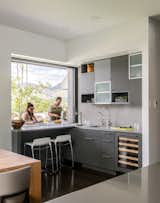 A pocket window in the kitchen allows for a double-sided bar area, with access to the outside grill. “It’s a great place to sit and drink your morning coffee and enjoy the views,” said Goff, who placed two Tiffany counter stools at the pass-through bar. The kitchen cabinets are a mixture of rift-cut white oak and cabinets painted in Benjamin Moore’s low-gloss Iron Mountain hue, with Caesarstone countertops.  Photo 3 of 4 in Dva by Dusko Amrich from Inside Out