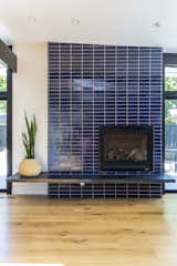 A new gas fireplace with floating steel hearth features Fireclay Tile's brick tile in a bold blue tone.