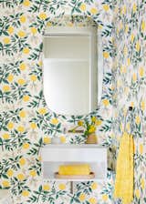 A large condo in San Francisco's Pacific Heights neighborhood has a powder room whose cheery wallpaper has pops of yellow, which are repeated throughout the space with accent towels.