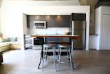 Antique drafting table at same height as counters acts as an island. National Public Seating stools match the rest of the grey colour scheme.