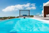 An incredible, glass-walled swimming pool overlooks the turquoise waters.