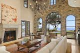 The soaring great room features a large fireplace and elegant arched windows opening to the pool and ocean beyond.