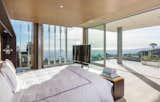 A glass-enclosed master suite is equipped with automatic shades and sliding glass doors to a large terrace that appears to float weightless over the lights of Los Angeles.
