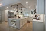 An incredible chef's kitchen boasts an oversized, eat-in single-slab marble island and backsplash.