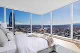 A corner master bedroom suite captures panoramic city views through towering window walls with built-in power window shades.