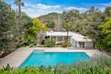 A large swimming pool is nestled against lush, landscaped hills. 