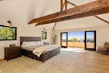 The light-filled master suite with exposed beams and a private balcony overlooking the city.