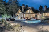 The idyllic, resort-style backyard features a screened-in and heated covered porch, two wood-burning fireplaces, a hot tub, a pristine swimming pool with a water feature, a gorgeous cabana with an entertaining area, a changing room, and an outdoor bar with a barbecue and pizza oven. 