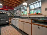 Kitchen, Granite Counter, Ceiling Lighting, Laminate Cabinet, Refrigerator, Open Cabinet, Range, White Cabinet, and Drop In Sink Kitchen with commercial range and rubber flooring  Photo 4 of 5 in The Auerbach House by Sarah Sonke at ModHomes Realty