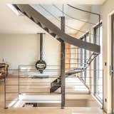 Finesse de la structure et transparence d’un escalier construit devant une large baie vitrée.
Un défi technique résolu grâce à l’implantation d’un poteau acier carré autour duquel s’enroule un hélicoïdal sur trémie carrée, qui se termine par une volée droite.
Placer un escalier contre une baie vitrée nécessite d’affiner au maximum la structure (limons et marches) en acier de 10 mm d’épaisseur.
Le résultat : une transparence douce et agréable ouvrant sur une large terrasse suspendue.

