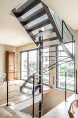 Finesse de la structure et transparence d’un escalier construit devant une large baie vitrée.
Un défi technique résolu grâce à l’implantation d’un poteau acier carré autour duquel s’enroule un hélicoïdal sur trémie carrée, qui se termine par une volée droite.
Placer un escalier contre une baie vitrée nécessite d’affiner au maximum la structure (limons et marches) en acier de 10 mm d’épaisseur.
Le résultat : une transparence douce et agréable ouvrant sur une large terrasse suspendue.

