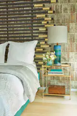 California mid-century modern lamps have their pattern echoed in the contemporary wallpaper by Inspirations. The wallpaper was chosen as a visual bridge to the High Line outside with its peeling birch bark trunks. The custom headboard in blackened wood with brass accents and turquoise bedframe are by Jarret Yoshida Inc. The box is vintage Japanese.