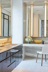 Marble and brass in the master bathroom become even more glamorous with gold-toned accents. The scheme is carried throughout with the addition of the gold and gray wallpaper reflected from the main hallway seen reflected in the vanity mirror.
  Photo 8 of 12 in Chelsea High Line by Jarret Yoshida Inc.