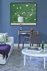 Guest rooms and dens should remain as beautiful as the rest of your home. Accents of color like this blue feature wall keep the room visually engaged and tie it to the now-connected living room. The Holly Hunt chair sits next to a desk lit by a mid-century Laurel table lamp that we replated. 