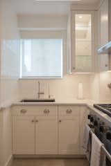 A signature design solution, one of our custom cabinets with both glass front, side and shelves is the perfect accompaniment for this kitchen sink and window area allowing light to flood the space. Handmade subway tiles from Cancos Tile reflect the colors of the incredible Manhattan view beyond the window.