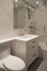 Every millimeter counts when transforming a compact bathroom into a jewel box perfect for pampering. Our signature small space custom vanity maximizes storage space with drawers shaped around plumbing. The shaped vanity top provides extra storage and is beautiful, durable pure white Ceasarstone for beyond easy maintenance. A mirrored Robern medicine cabinet is a minimal and elegant solution. Contemporary Newport Brass fixtures in a brushed nickel are a chic accompaniment to the Kohler sink and tub.