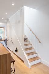 CAB Architects deftly hid appliances, pantry storage, and a litter box for the owners' two cats in the cabinetry beneath this staircase.