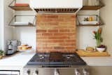 An existing brick chimney breast is reutilized as the backsplash for the range. 