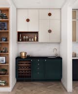 Between the kitchen and dining rooms is a "pass-through" bar or servery, with dark turquoise base cabinets with an integrated wine fridge and bar sink.