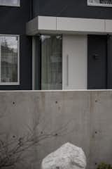 Entry sequence - Poured concrete fence wall in contrast to the dark stained cladding and aluminum front door. 