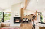 Open living/kitchen/dining with a three sided fireplace, exposed glulam beam, and american clay walls.