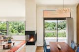 Open living/kitchen/dining with a three sided fireplace, exposed glulam beam, and american clay walls.