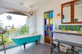 Living room cum master bathroom. Antique tub with mermaid feet! Antique cast iron wash basin, reclaimed French doors, custom vanity cabinet in walnut with chicken wire glass detail, Mercury Mosaics scallop tile backsplash. Andy Fleishman fantastique concrete floor tile. Sunrise specialty tub filler. Rohl sink faucets. Russ Morgan reclaimed glass pendant above tub. Vintage brass sconces at mirror. 