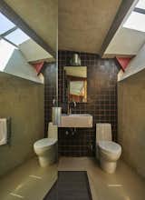 Bath Room, Ceramic Tile Wall, Wall Lighting, Wall Mount Sink, Two Piece Toilet, and Concrete Floor  Photo 11 of 13 in Escape to a John Lautner Micro-Resort in the Californian Desert