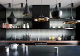 This dark and bold kitchen features Beat Pendants by Tom Dixon and a black-and-white tile backsplash by Popham Design.