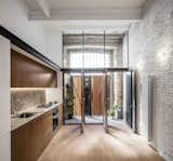Kitchen, Porcelain Tile Floor, Granite Counter, Wall Oven, Range, Accent Lighting, Wall Lighting, and Undermount Sink  Photo 5 of 13 in La Diana by Dwell from This Double-Height Apartment in 
 Barcelona Features Historic Details and a Floating Staircase