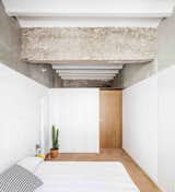 Bedroom, Bed, Porcelain Tile, Table, Wall, Storage, and Lamps  Bedroom Storage Porcelain Tile Wall Photos from This Double-Height Apartment in 
 Barcelona Features Historic Details and a Floating Staircase