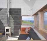 Living Room, Coffee Tables, Wall Lighting, Sofa, Wood Burning Fireplace, and Concrete Floor  Photo 9 of 11 in The Tinhouse by Dwell from Stay in a Modern Tin Cottage on Scotland’s Isle of Skye