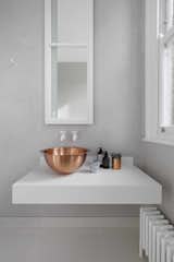 &nbsp;Though vessel sinks can be more costly to install, the color and material contrast between the basin and counter—as seen in this solid brass bowl sink on top of a custom Corian base—can add an extra layer of style to your bathroom.