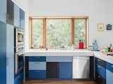 Go bold by painting your cabinet doors different colors. In this Tennessee home, laminate kitchen cabinets in three shades of blue and a Corian top in Glacier White completes a fun and modern composition.