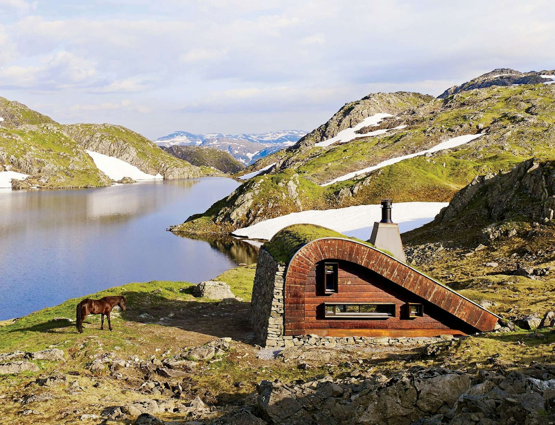 Tucked away on the edge of a small lake surrounded by mountains in western Norway, the 376-square-foot Bjellandsbu cabin by Snøhetta is made with locally sourced stones and <a href=