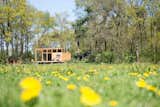 Outdoor, Field, Trees, Grass, and Shrubs Overlooking a peaceful meadow in the province of Overijssel in the Netherlands, is a snug 452-square foot prefab wooden hut with large windows that blur the bounderies between indoor and outdoor spaces. Build in two modules then transported and assembled on site, the house, which was constructed mainly with Oregon pine, arrived on location complete with bathroom, kitchen, couches, table, inner walls, cabinets, beds and floors. Custom-designed furniture such as a sofa integrated into a sunken living area, and a U-shaped corner bench imbues this little hut with plenty of quirky charm.  Photo 6 of 7 in 7 Incredible Prefab Homes You Can Rent For Your Next Holiday