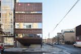 Sited on a typical 25-by-100-foot corner lot in Brooklyn, this 5,000-square-foot residence was built with 21 stacked shipping containers cut diagonally along the top and bottom to create a step-like structure with four tiered levels and a small pool between the two lower levels.